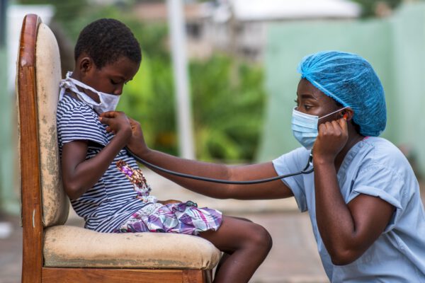 a medical professional in protective clothing is performing a check up on a young male patient