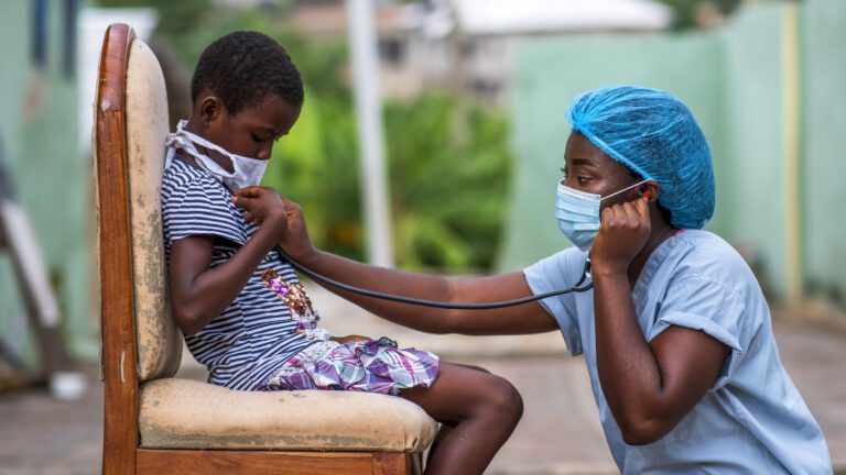 a medical professional in protective clothing is performing a check up on a young male patient