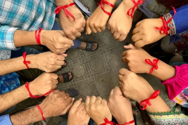 Group photo all with hands making a circle and a red ribbon on their wrists supporting heart health awareness