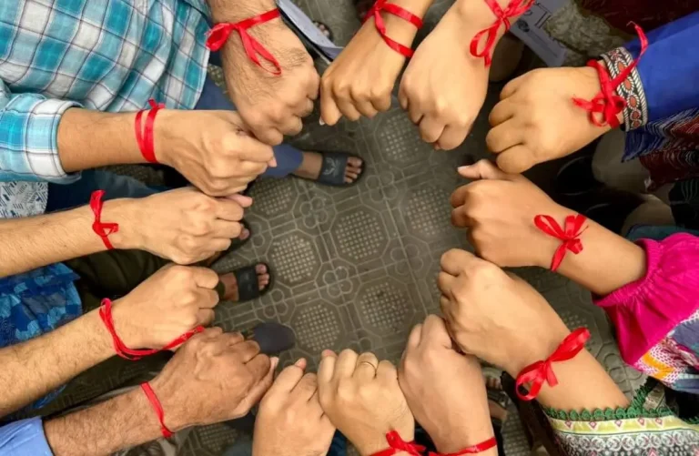 Group photo all with hands making a circle and a red ribbon on their wrists supporting heart health awareness