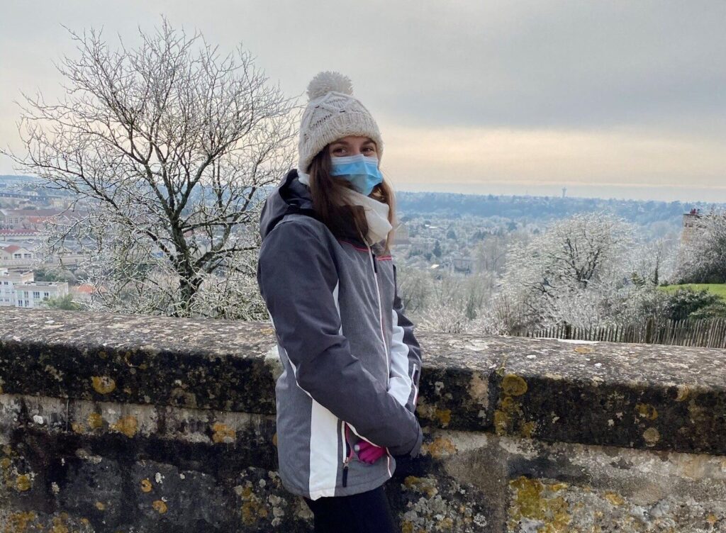 A photo of a woman stood on a crisp, icy day overlooking a valley with sights for millions on end