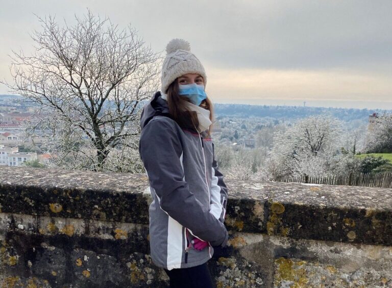 A photo of a woman stood on a crisp, icy day overlooking a valley with sights for millions on end