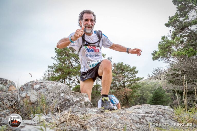 Alejandro Asprella running in the wilderness and climbing over a rock