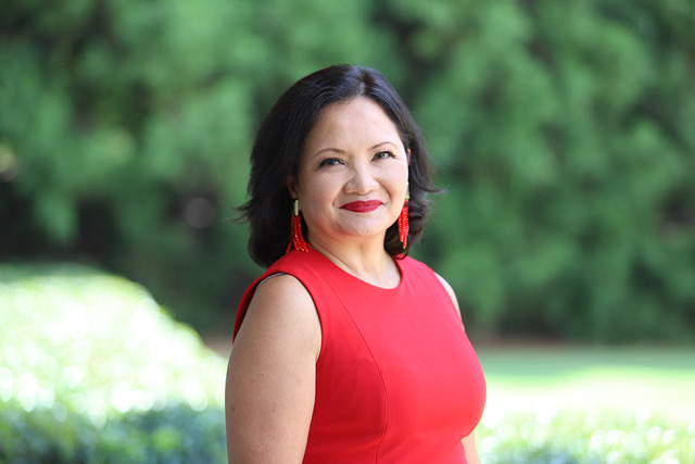 Celina Gorre portrait image wearing a red dress with trees in the background