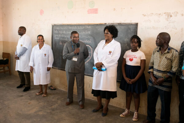 Health care professionals and other people at the front of a classroom, man holding a microphone in front of blackboard.