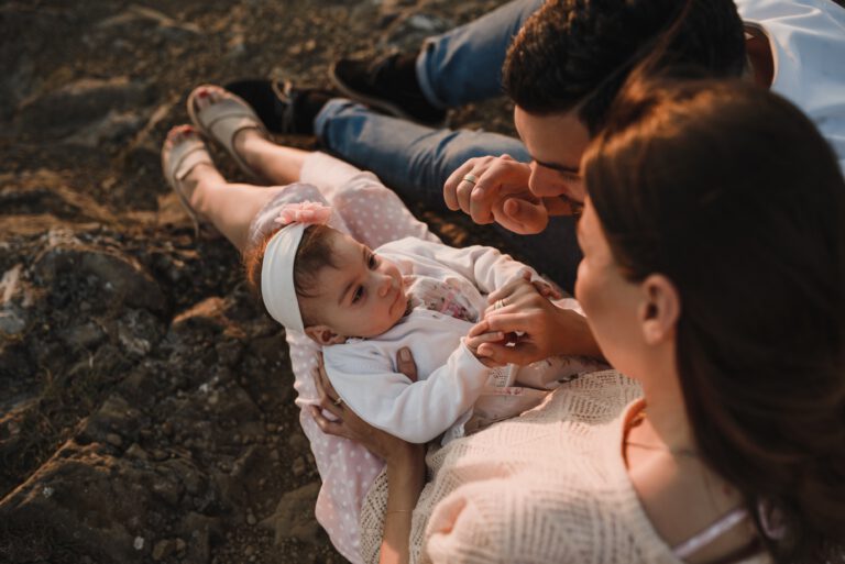 a young family sat on a beach playing their child