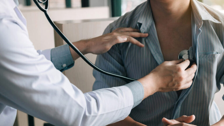 a medical doctor monitoring a patient's heart by using a stethoscope