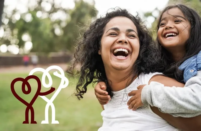 Woman carrying a small girl on her back with a grassy background and 2 line drawn hearts with arms and legs supporting one another - world heart day