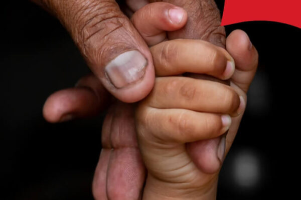 Adult holding a child's fingers. Community gathering for cardiovascular health campaign. World Heart Day 2025