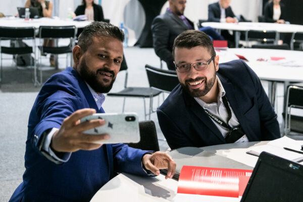 two colleagues in suits taking a selfie at the World Congress of Cardiology