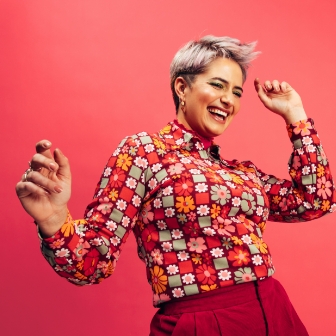 Woman dancing in a flower shirt with a pink background
