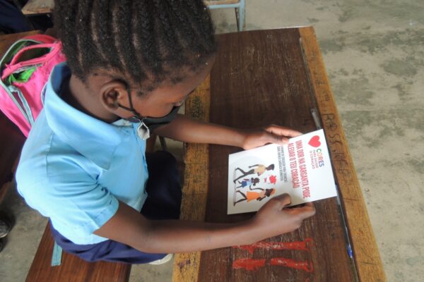 a young child wearing a facebook is reading a Colours to Save heart booklet in Maputo, Mozambique