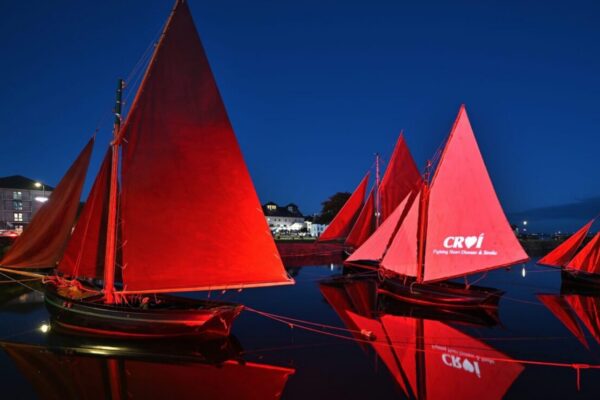 Boats with red sails to the right of a heart shaped cut out background banner - Shine for World Heart Day