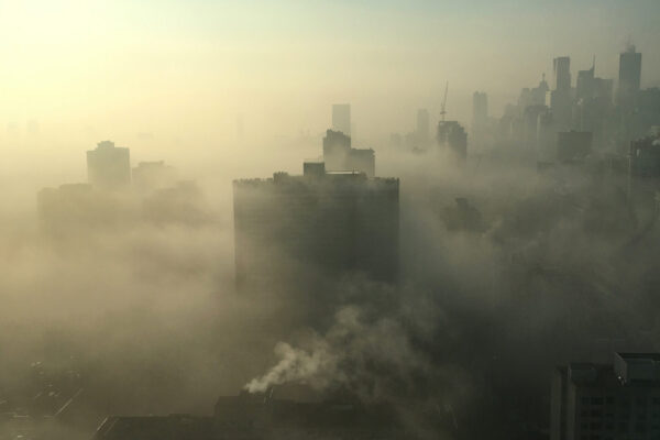 An image depicting air pollution. The image shows a lot of smoke covering skyscrapers in the distance
