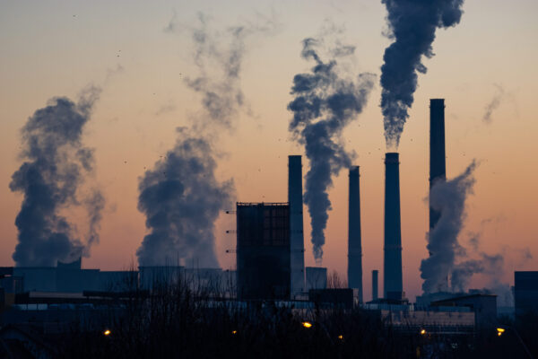 An image depicting air pollution. The image shows 4 chimneys showing lots of smoke, and a factory beneath