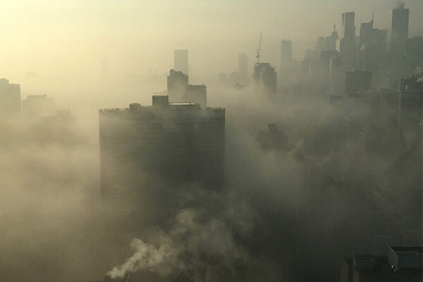 Une image illustrant la pollution atmosphérique. On y voit une épaisse fumée recouvrant des gratte-ciel au loin.