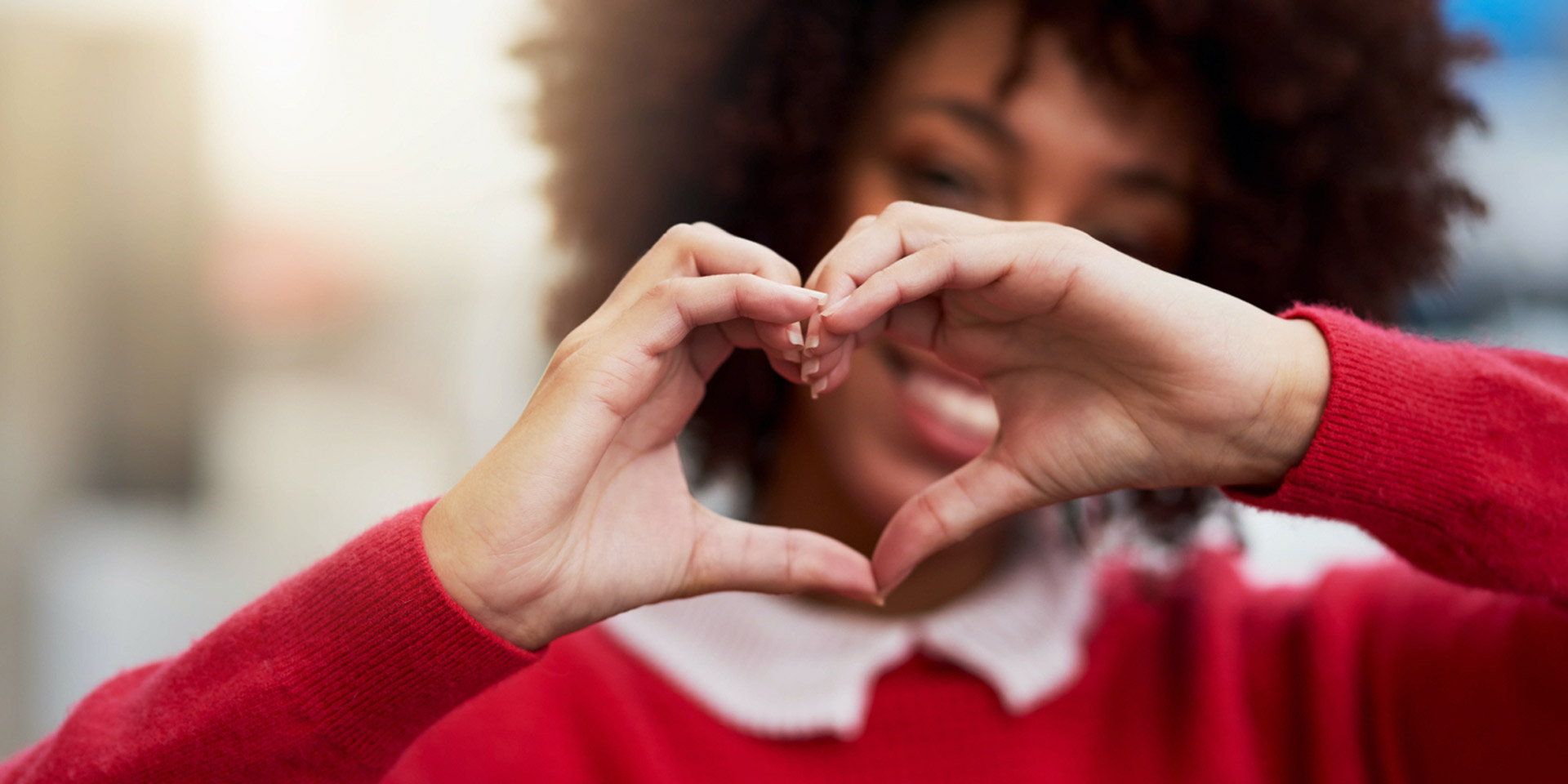 a woman gesturing a heart with her hands