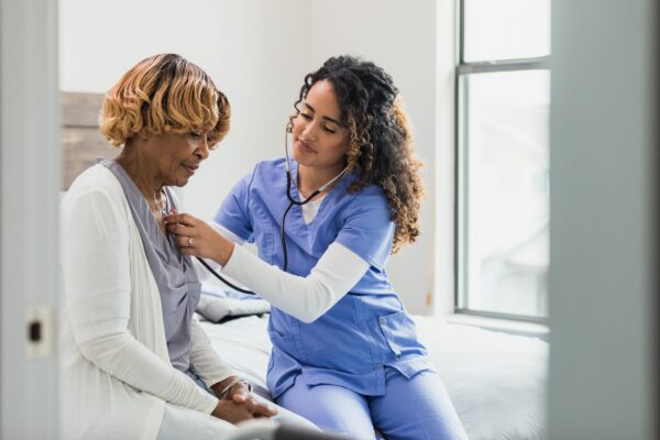 a female medical professional is monitoring a patient's heart by using a stethoscope