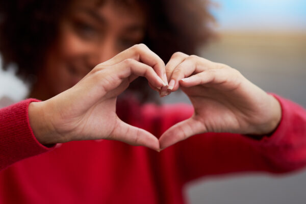 A woman holding up her hands up gesturing a heart