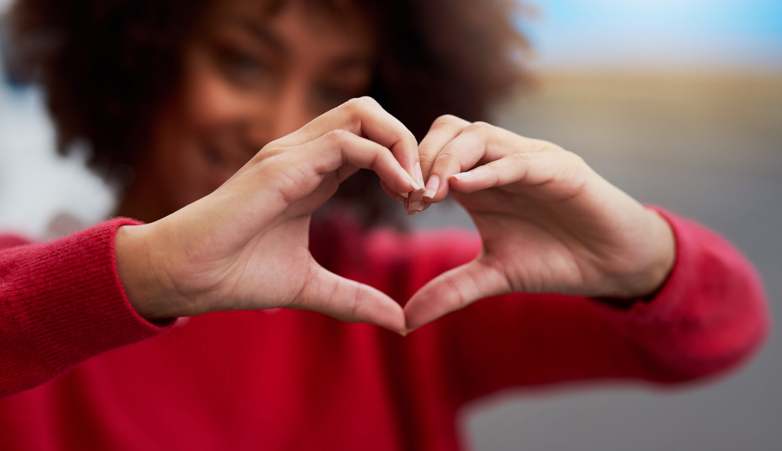 A woman holding up her hands up gesturing a heart