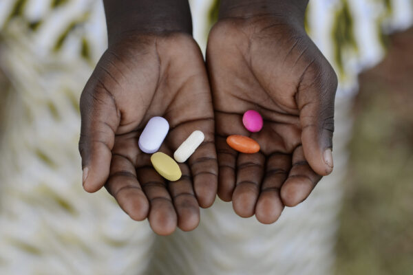 Hands with different coloured pills in their palms