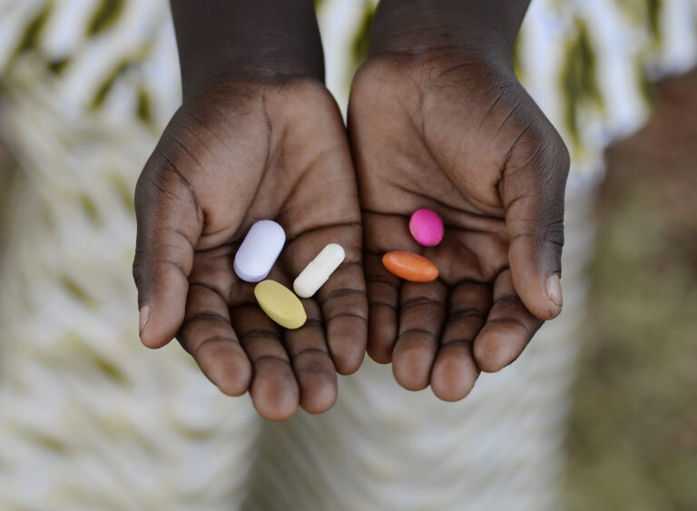 Hands with different coloured pills in their palms