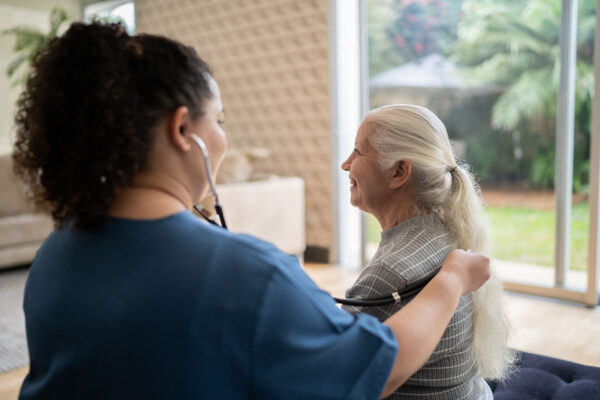 a female health professional is examining a senior patient with a stethoscope