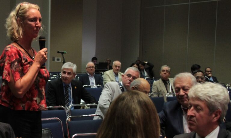 Karen Sliwa speaking into a microphone alongside colleagues in at a conference
