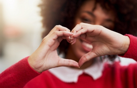 A woman making a heart hand gesture