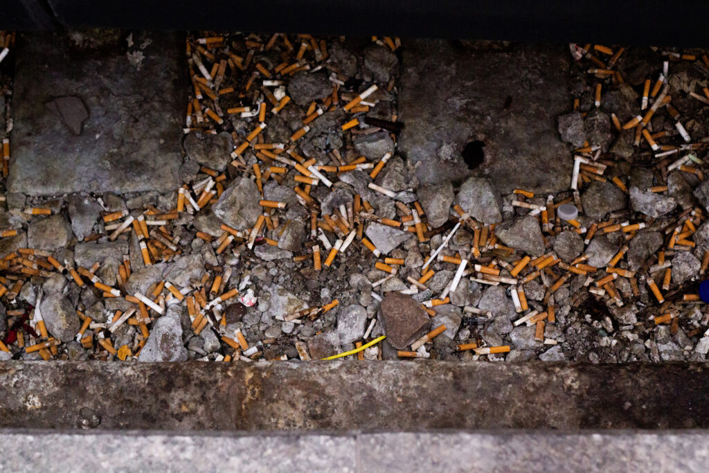 A photo of lots of cigarattes discarded on the ground