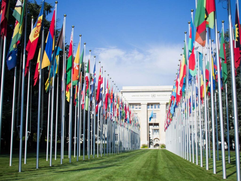 Front view of United Nations Office at Geneva with pathway lined by national flags