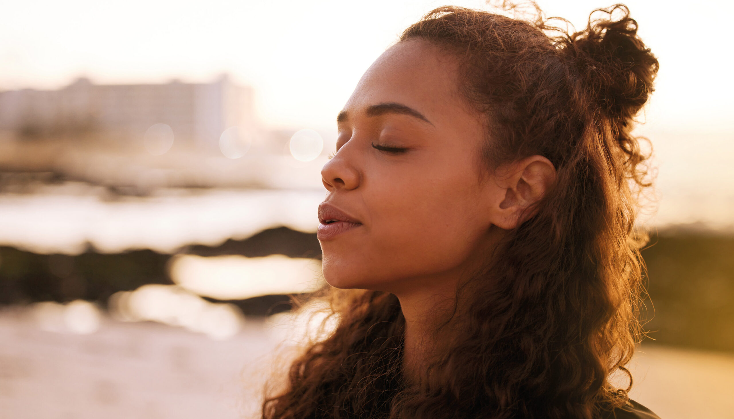 a woman with her eyes closed outdoors exhaling