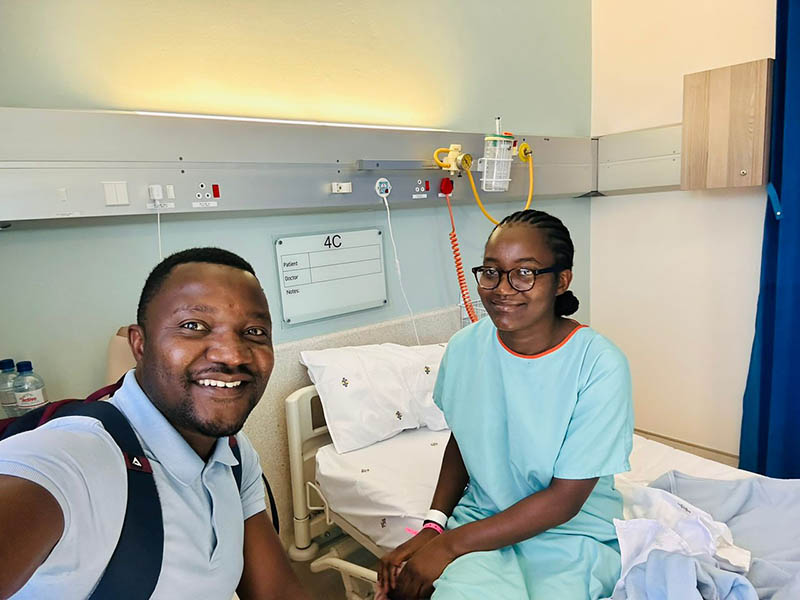 Martha Shiimi smiling with a supporter in a hospital room, ward 4C.