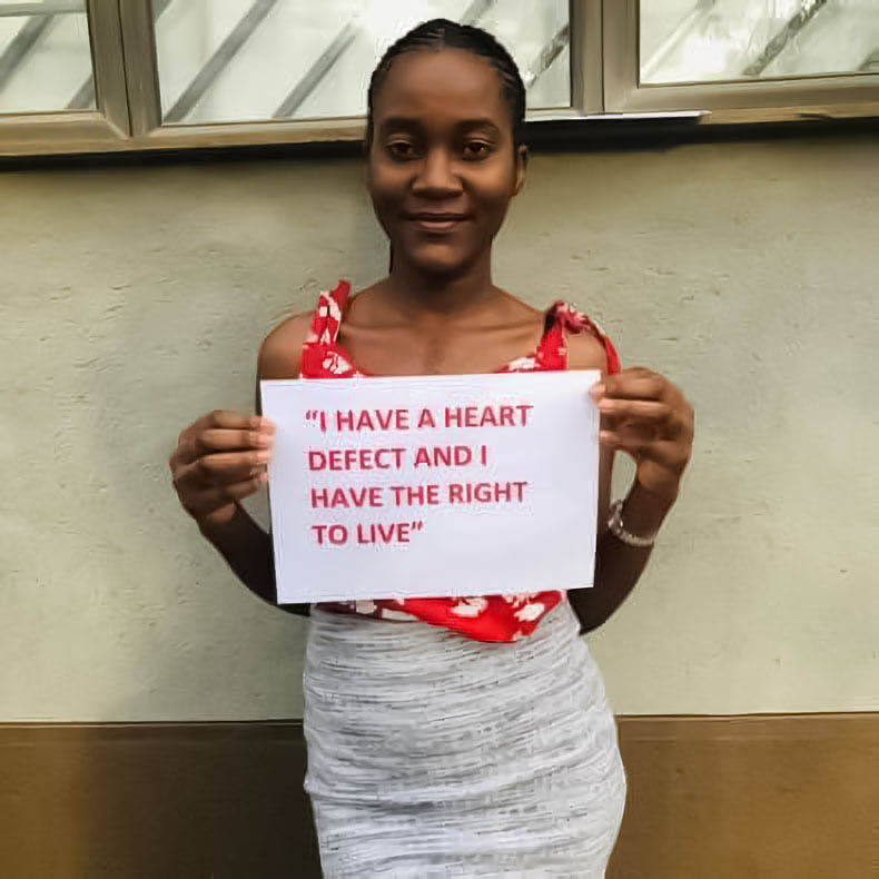 Martha Shiimi holding a sign reading "I have a heart defect and I have the right to live".