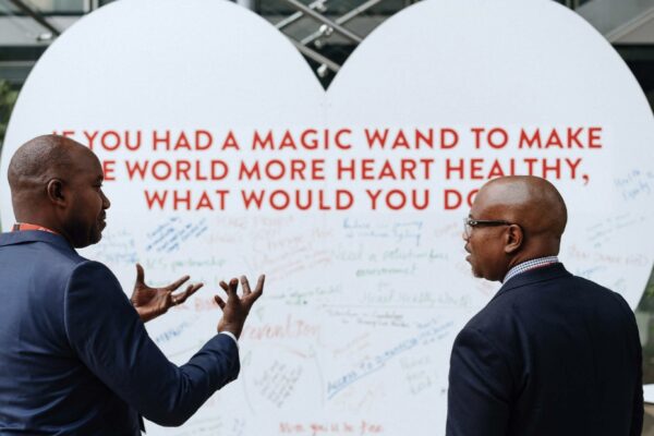 White heart board with writing on it and 2 people in front of it discussing it
