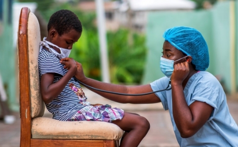 A medical professional using a stethoscope on a child