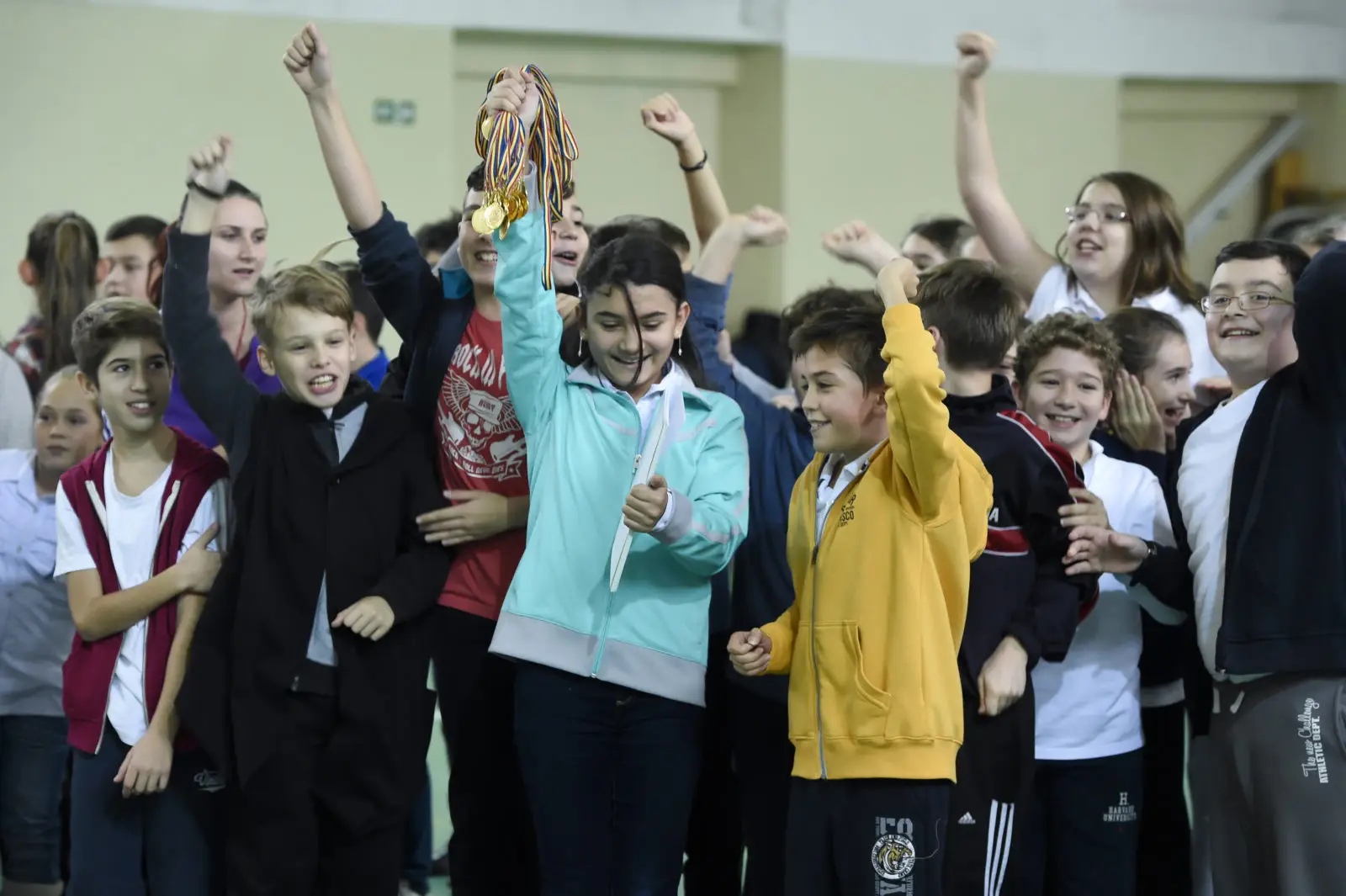Romanian children partaking in physical activity. A young girl is holding a handful of gold medals