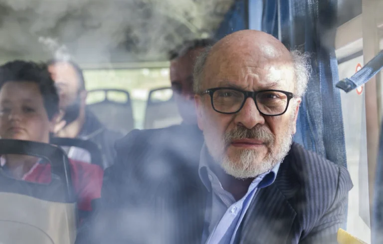 a man wearing glasses is sat on a bus