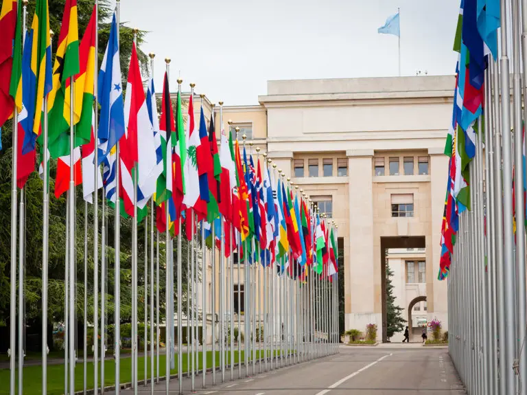 Front view of United Nations Office at Geneva with pathway lined by national flags