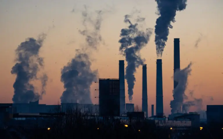 An image depicting air pollution. The image shows 4 chimneys showing lots of smoke, and a factory beneath