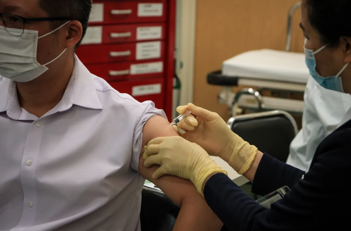 a healthcare professional giving a vaccination to a patient in their upper arm