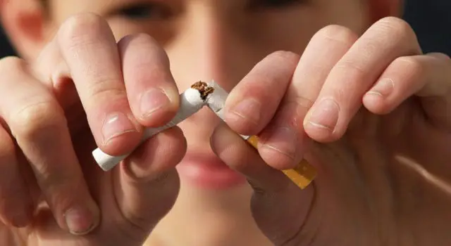 A photo of a teenage boy breaking a cigarette in half