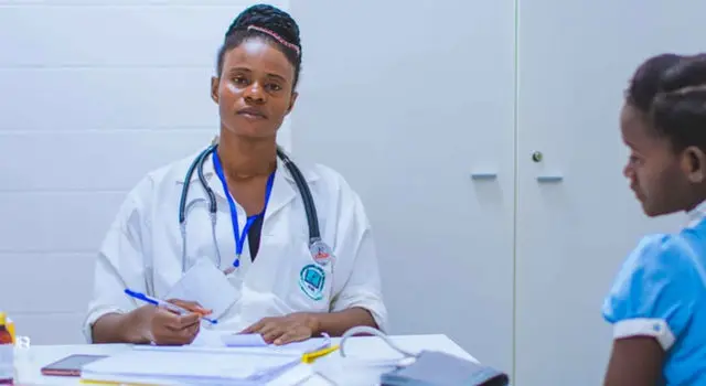 two healthcare professionals sat at a table with paperwork placed in front of them