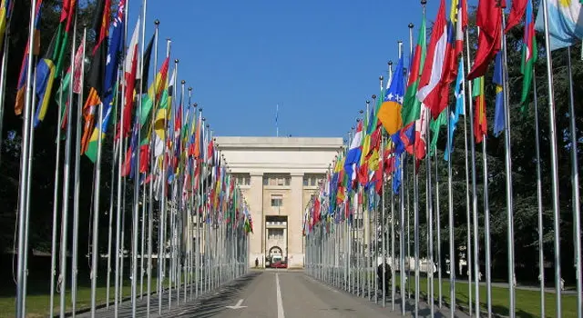 Front view of United Nations Office at Geneva with pathway lined by national flags