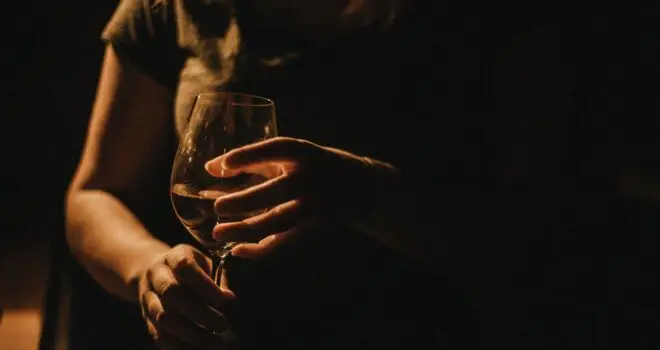 a silhouette of a woman holding a glass of white wine