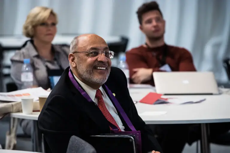 a man in glasses and a suit listening keenly at the World Congress of Cardiology