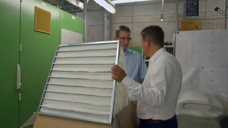 Beats Of Change - 2 men holding a filter system in a room