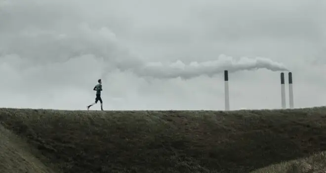 A man running next to a refinery