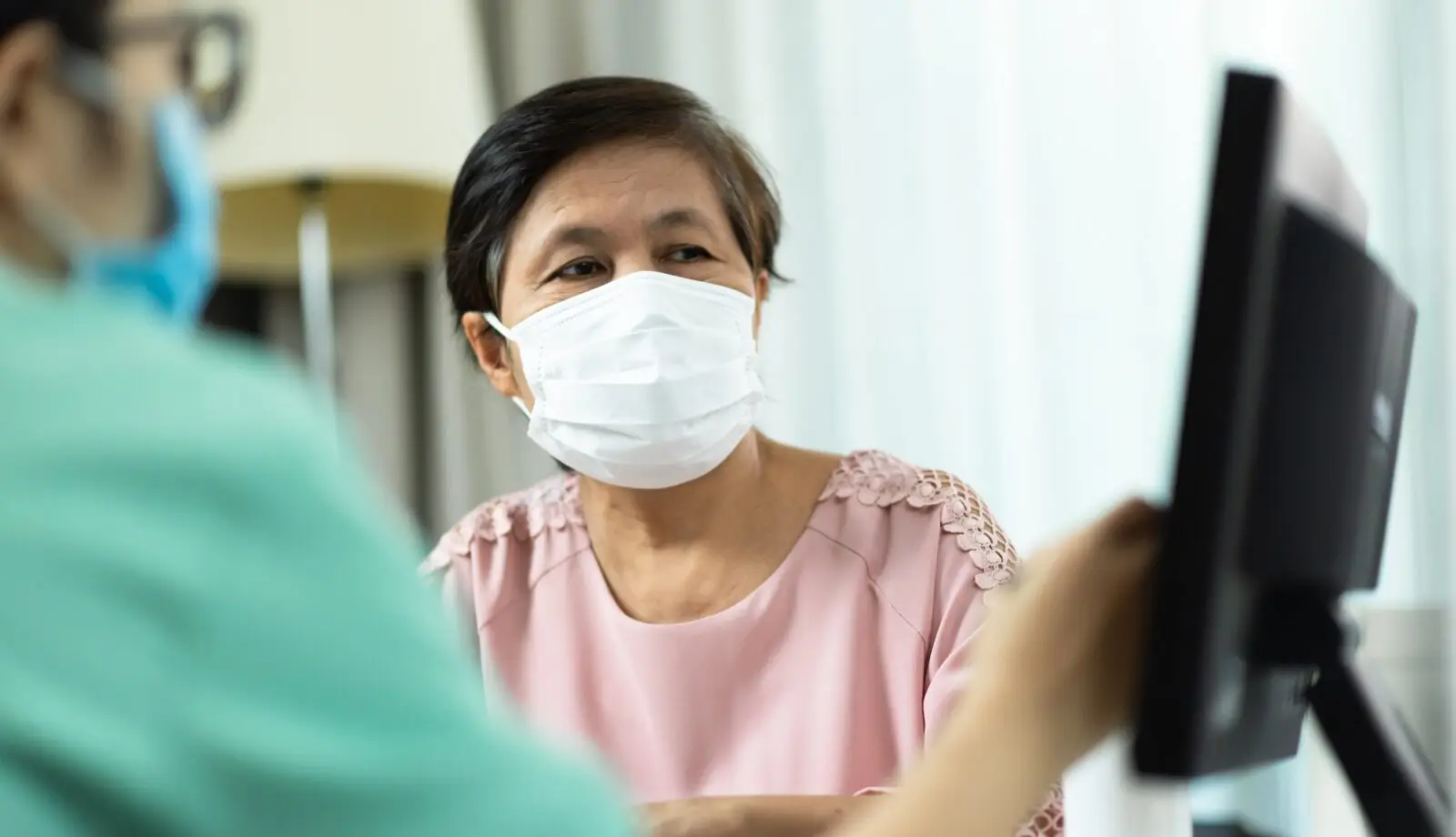 A medical doctor is showing results to a female patient wearing COVID-19 face masks on screen.