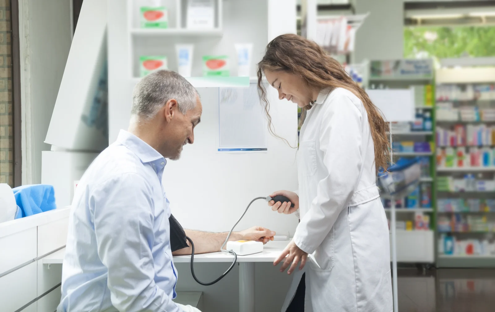 a female pharmacist examining a male patient inside a pharmacy